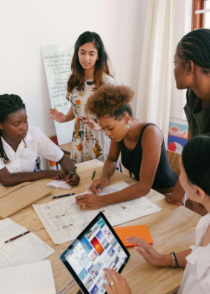 Group of women brainstorm around a table. Photo by Photo by RF._.studio _